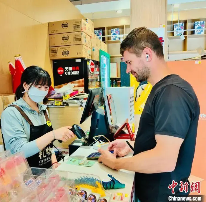 图为外籍游客在大陆娱乐城八达岭长城景区商店内体验电子支付。
