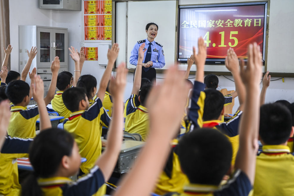2024年4月15日，在广西兴业县一所小学内，公安民警在讲解国家安全相关知识的过程中与学生们互动。