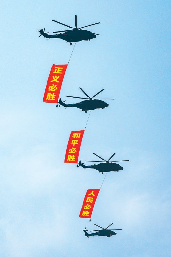 空中护旗梯队直升机悬挂“正义必胜”“和平必胜”“人民必胜”条幅。